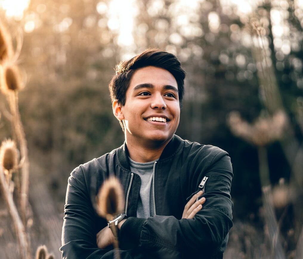 smiling man standing near green trees